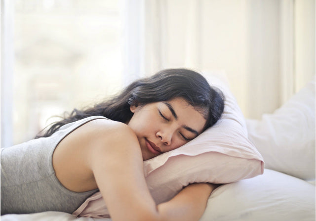 woman lying on her stomach, sleeping while hugging a pillow